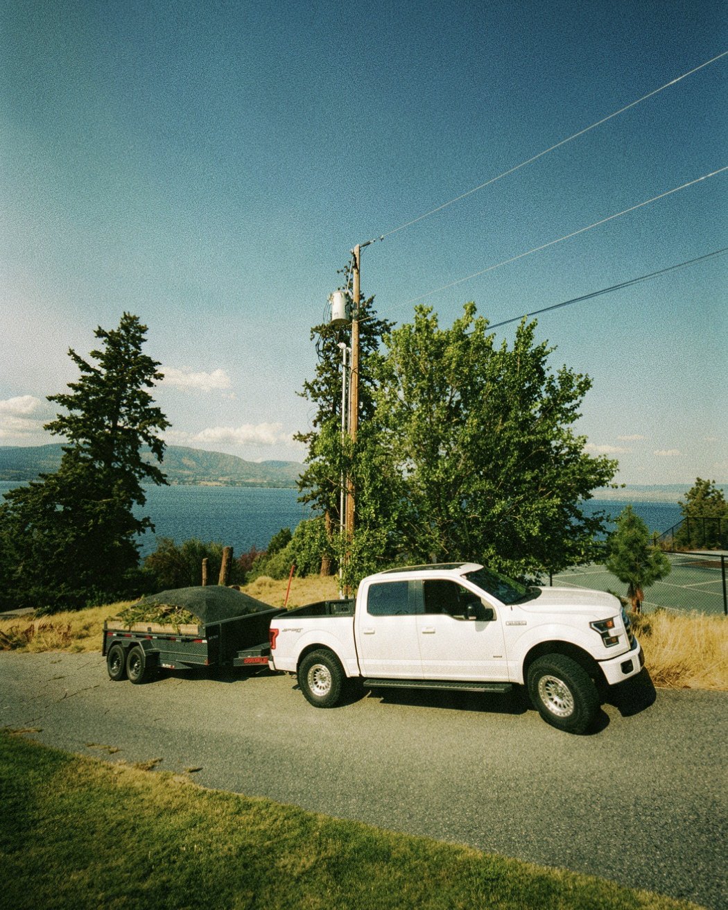 Service truck and loaded trailer parked above Okanagan Lake during a wildfire protection job
