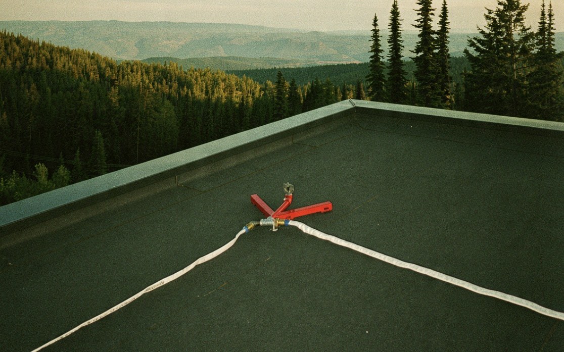 Wildfire sprinkler head mounted on a rooftop overlooking forested Okanagan hillsides