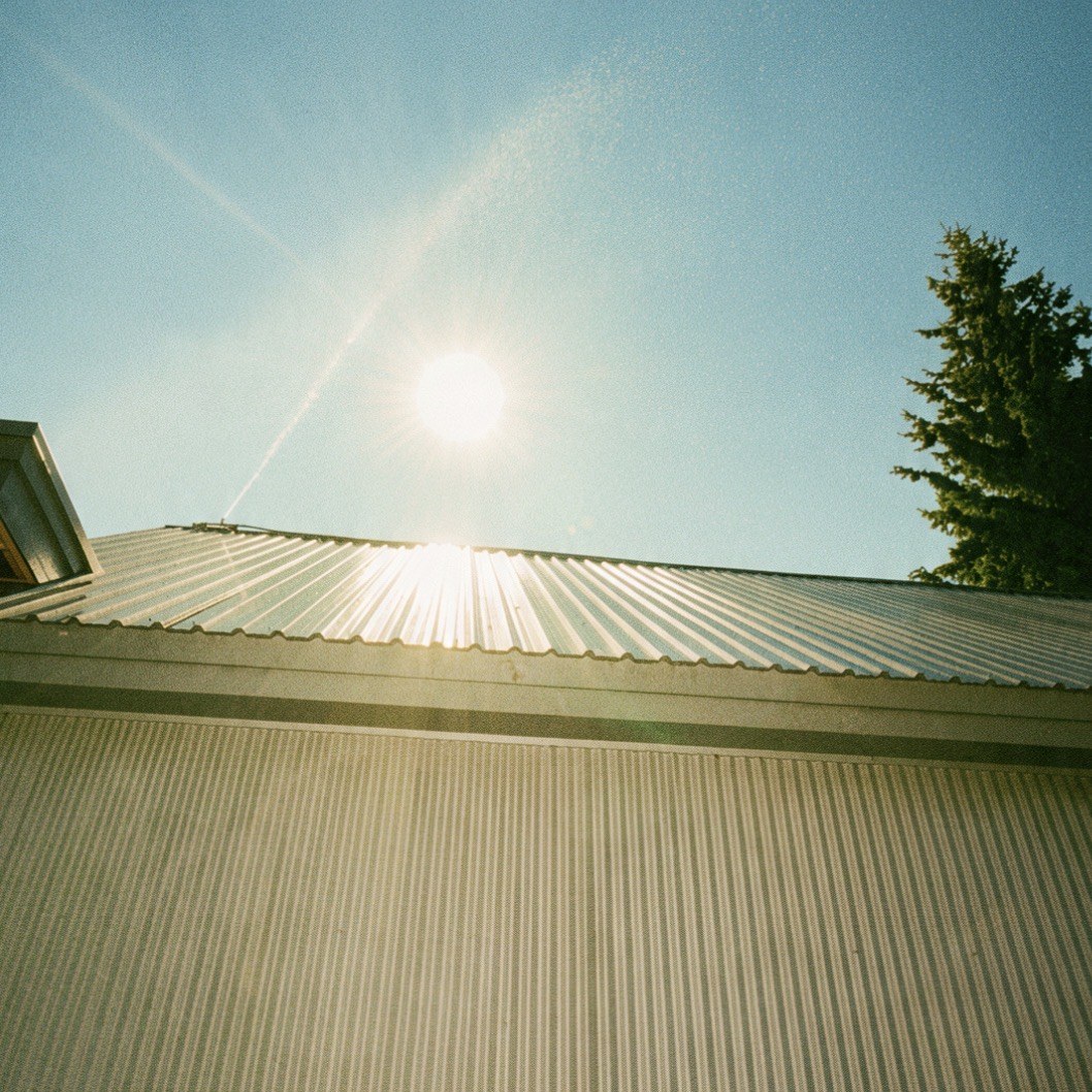 Wildfire sprinkler misting over a metal roof against the afternoon sun