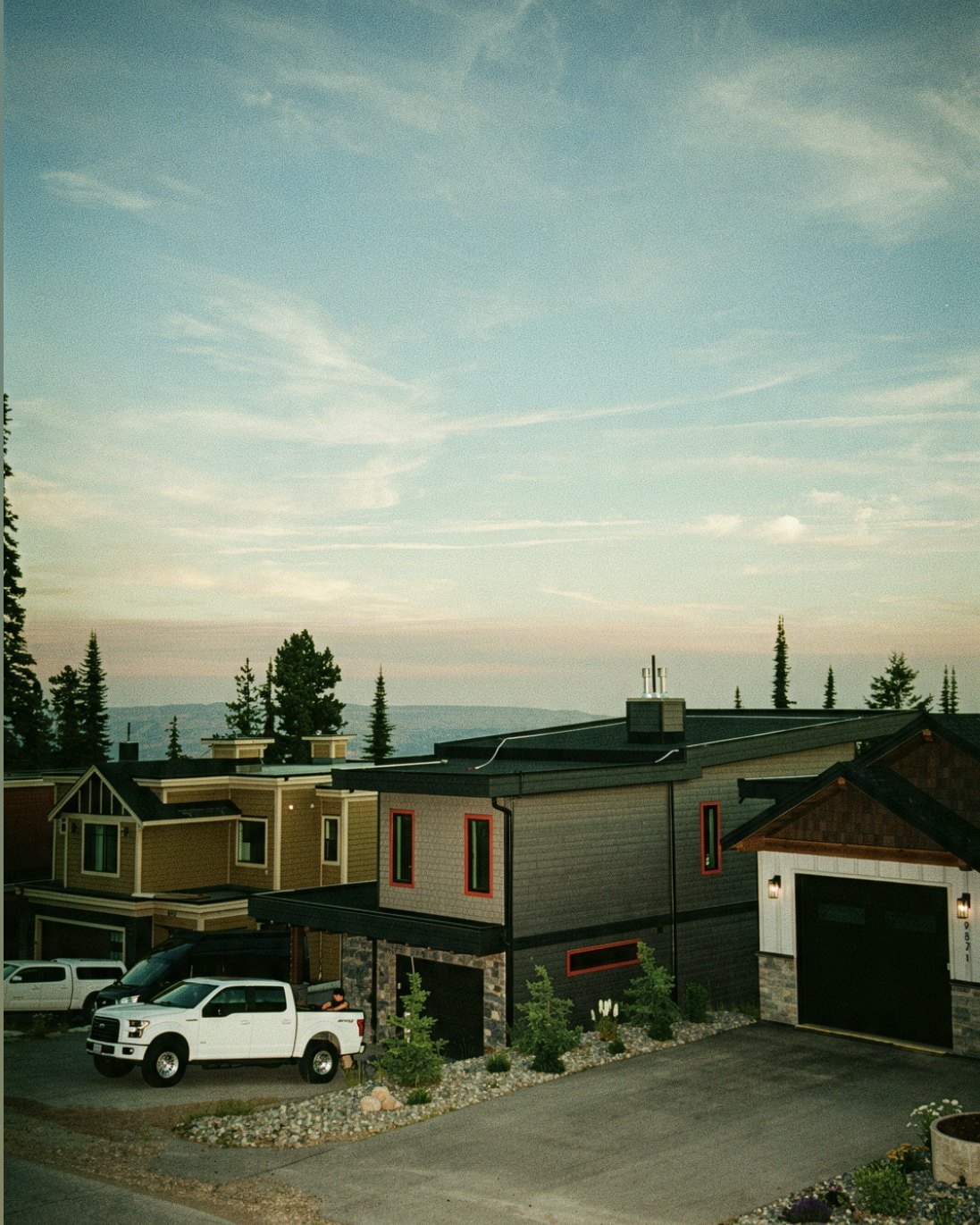 Hillside Okanagan home protected by a rooftop wildfire sprinkler system at dusk